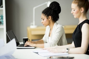 Photo of two women working at a desk in an office