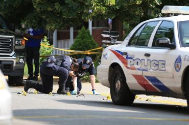 Photo of Toronto police examining shells and blood stains on street after shooting 