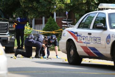 Photo of Toronto police examining shells and blood stains on street after shooting