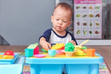A young asian boy plays with colourful plastic toys