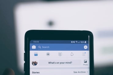 close up of smartphone with facebook app up. Text on screen reads "what's on your mind?"