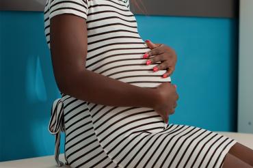 A Black woman holds her pregnant belly