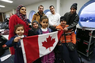 Syrian refugee family holding a Canadian flag