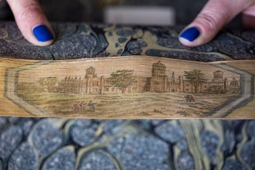 A fore-edge painting book's pages are fanned back to reveal an intricate illustration