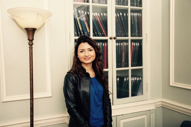 Mavra Ahmed smiling and standing in front of a bookshelf