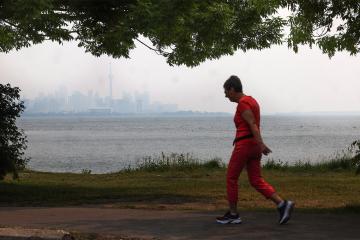 an elderly woman jogs along the waterfront on Toronto Island