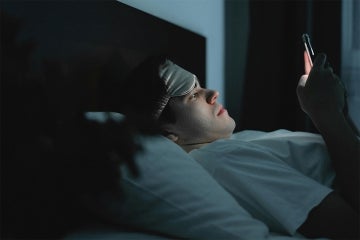 man lying in bed in the dark reading his cell phone