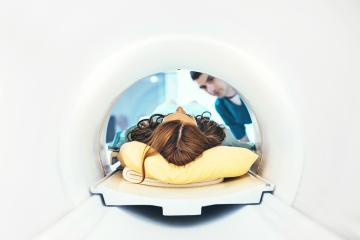 a technician helps a woman into an MRI machine