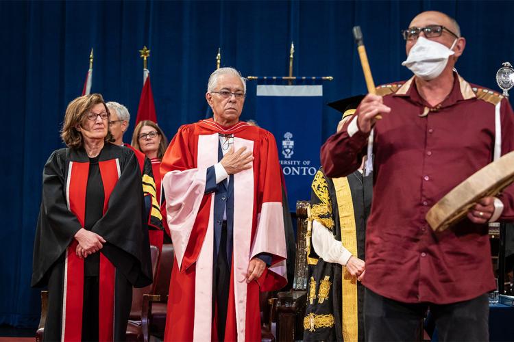 Robert Houle looks on as Professor Archer Pechawis plays an honour song in his honor