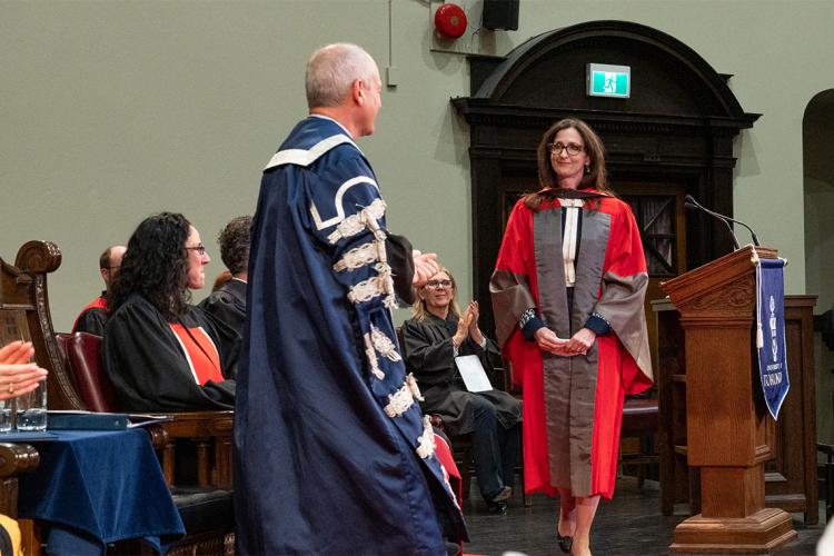 Sara Seager crosses the stage to greet President Meric Gertler