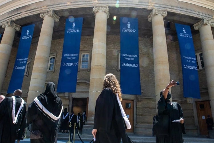 student takes a selfie in front of Convocation Hall at the University of Toronto