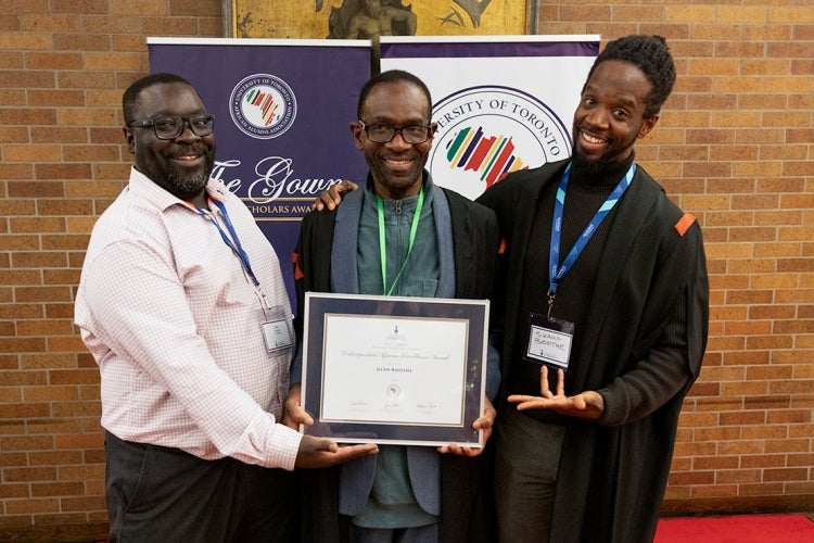 Glen Boothe smiles proudly as he hold up his award and is flanked by his two sons