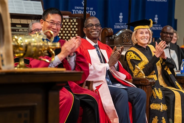 Patrick Awuah smiling on stage during convocation with Dean Chris Yip and Chancellor Rose Patten