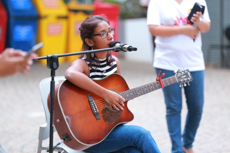 Rashmi de Silva Wijeyeratne playing the guitar and singing in public